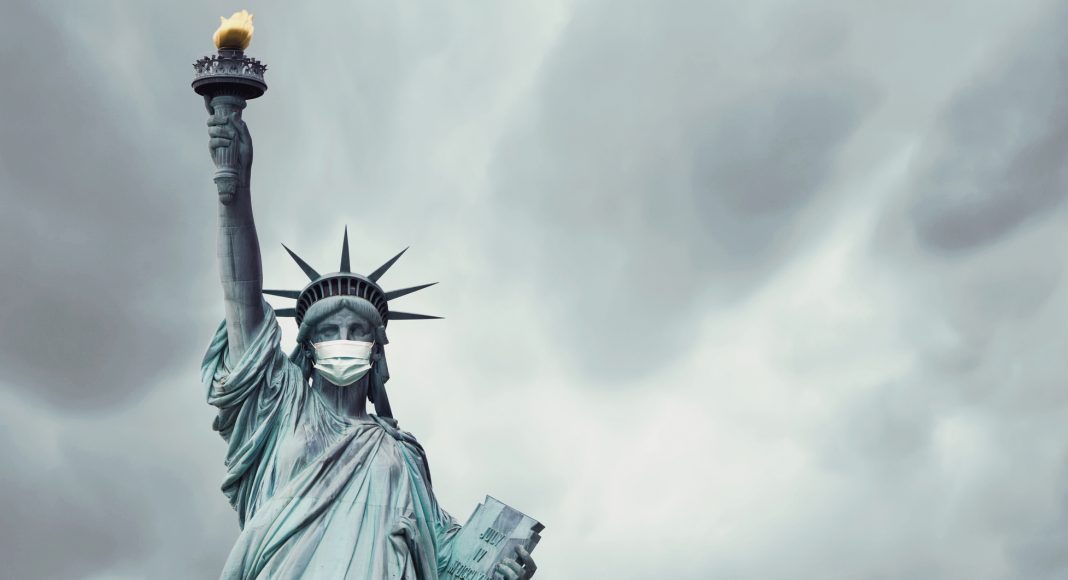 Stock photo of the New York's Statue of Liberty with a mask on its face caused by the coronavirus covid-19 and copy space on the right