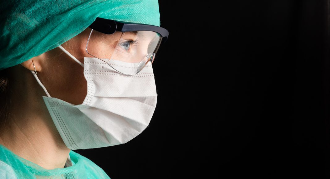 Medical worker with face mask goggles and protective suit