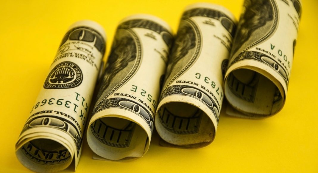 Roll of American dollars banknotes o yellow background --stock photo